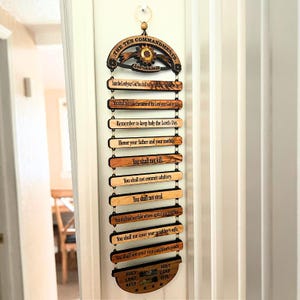 May include: Wooden wall hanging featuring the Ten Commandments. The top section reads "THE TEN COMMANDMENTS" and "Jerusalem." Each commandment is printed on a separate wooden slat. The bottom section includes the words "HOLY LAND WATER" and "HOLY LAND OIL."