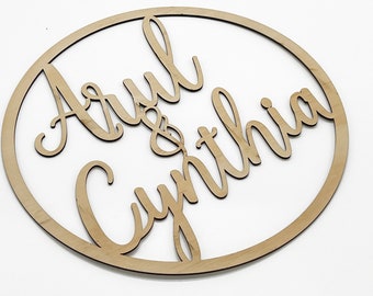May include: A wooden circle with the names "Arul & Cynthia" written in cursive script.