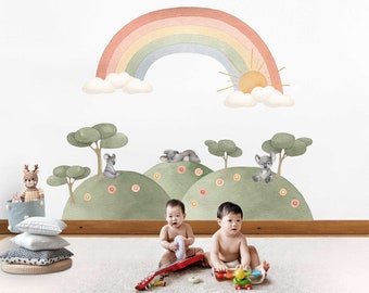 May include: Two babies playing on a white rug with a rainbow, clouds, and sun wall decal. The decal also features trees and koalas. One baby is playing with a red toy guitar and the other is playing with a toy car.