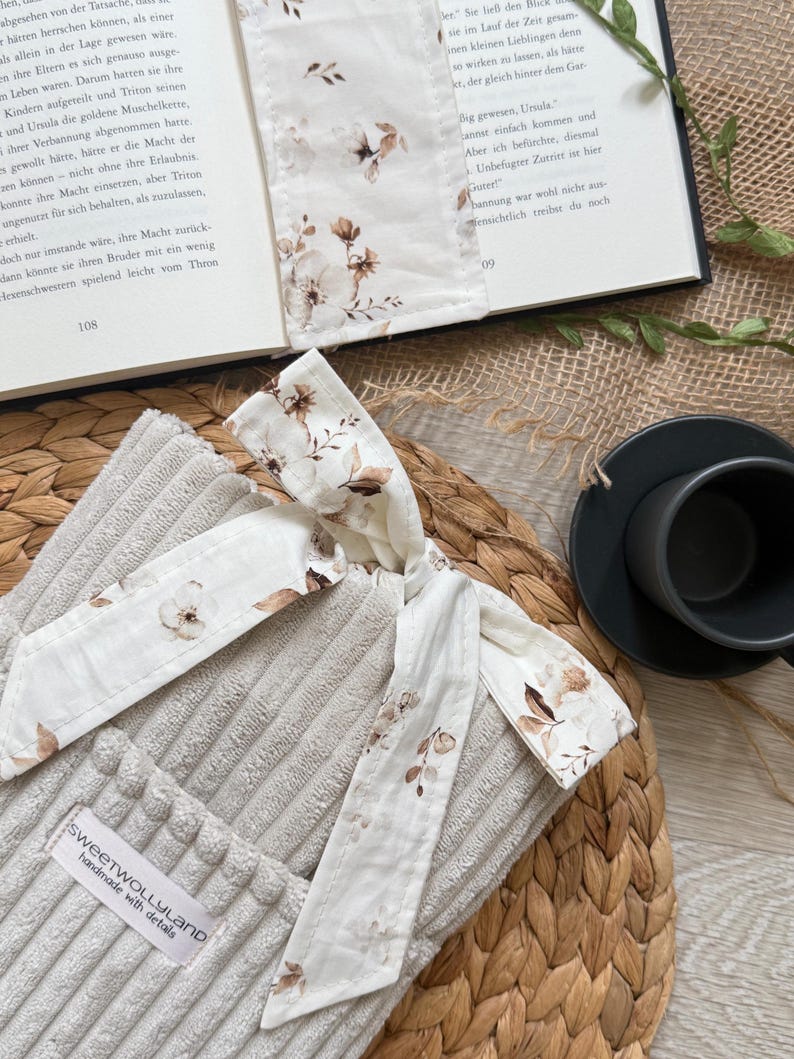 Weich gepolsterte Booksleeve mit floralem Schleifenverschluss – einzigartiges Design für Leseratten und Geschenkidee Romantische Buchhülle im Vintage-Look – handmade aus Cordstoff mit zarter Schleife, perfekt für Bücher oder Journals.