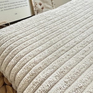 Beige Buchtasche mit Rippenstruktur und floraler Baumwollschleife – handgefertigt, weich gefüttert und perfekt für deinen Leseschatz. Handgenähte Buchhülle von Sweetwoollyland – gemütlicher Stoff in Naturtönen, verziert mit einer liebevollen Schleife.