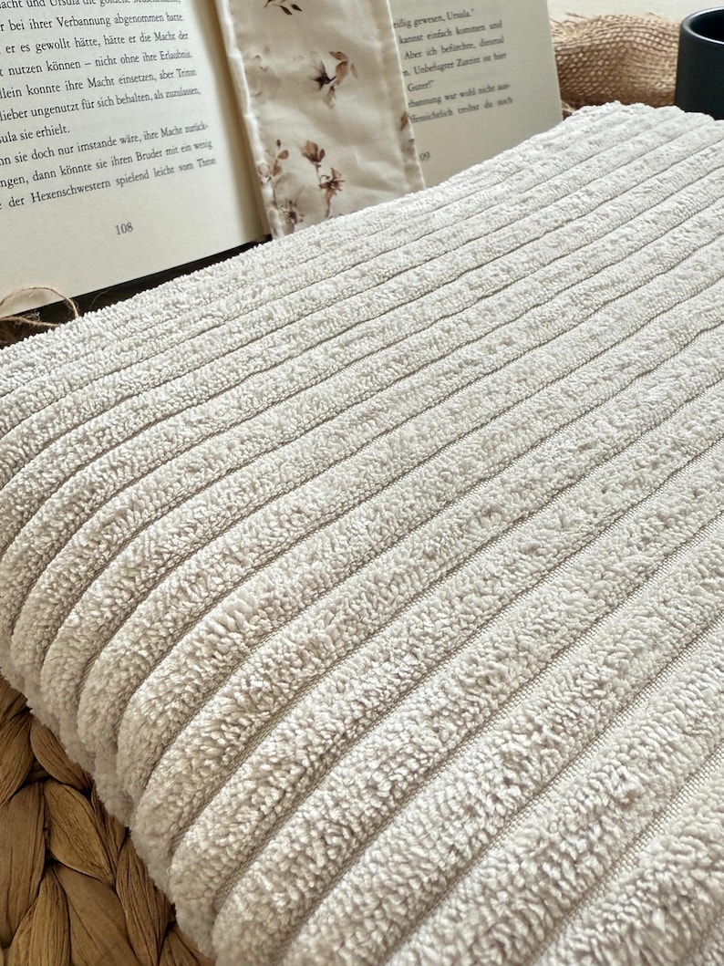 Beige Buchtasche mit Rippenstruktur und floraler Baumwollschleife – handgefertigt, weich gefüttert und perfekt für deinen Leseschatz. Handgenähte Buchhülle von Sweetwoollyland – gemütlicher Stoff in Naturtönen, verziert mit einer liebevollen Schleife.