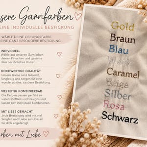 Farbübersicht der Garnfarben für die individuelle Namensbestickung handgemachter Buchhüllen von SweetWollyLand. Auf einem beigen Stoff sind die acht Stickgarnfarben Gold, Braun, Blau, Weiß, Caramel, Beige, Silber, Rosa und Schwarz zu sehen. Die liebevoll gestaltete Infografik in Creme und Rosé zeigt die Möglichkeiten zur Personalisierung, hochwertige und langlebige Stickerei sowie die individuelle Kombination der Garnfarben mit verschiedenen Stoffen und Designs.