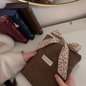 Weich gepolsterte braun Booksleeve mit leoprint Schleifenverschluss – einzigartiges Design für Leseratten und Geschenkidee Romantische Buchhülle im Vintage-Look – handmade aus Cordstoff mit zarter Schleife, perfekt für Bücher oder Journals.
