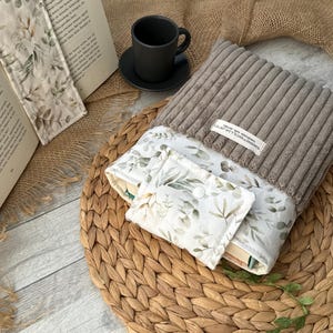 Gepolsterte Buchhülle für Taschenbücher, mit floralem Muster und Label „SweetWoollyLand“, schützt Bücher unterwegs.