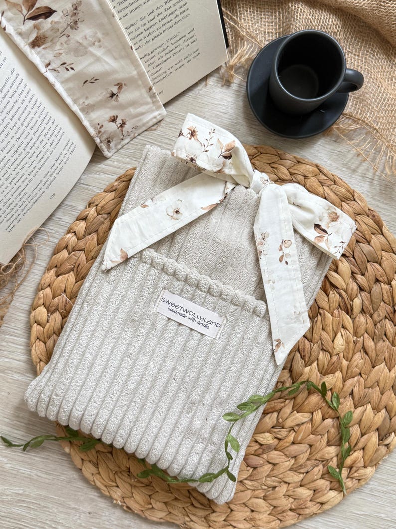 Ein Set aus Buchhülle mit Lesezeichen in einem super sofeten cremefarben Breidcord mit samt. Der Buchumschlag hat ein schlichtes, modernes Design.