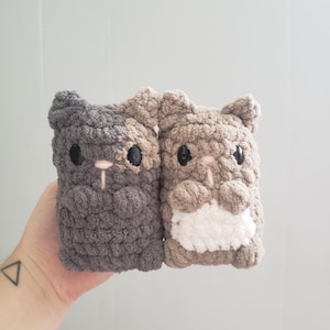 May include: Two crocheted plush toys shaped like animals with brown and white fur. The toys are sitting side by side and have black eyes.