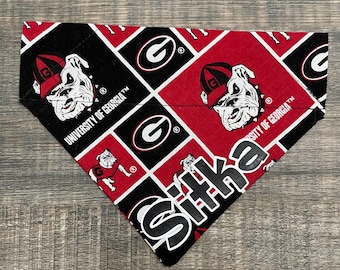 May include: Red and black bandana with a repeated pattern of the University of Georgia logo, a bulldog mascot, and the text "University of Georgia". The bandana is trimmed with black stitching.
