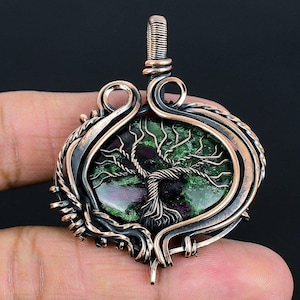 May include: A copper wire wrapped pendant featuring a green and pink gemstone with a tree of life design.