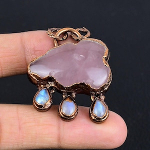 May include: A pink rose quartz pendant with a copper frame and three teardrop moonstone accents.