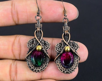 May include: A pair of copper wire wrapped earrings with a green and purple gemstone in each. The earrings have a gold accent in the center.