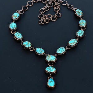 May include: A turquoise and copper necklace with a pendant. The necklace has a chain with oval-shaped turquoise stones set in copper.