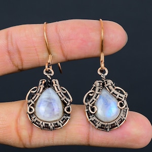 May include: A pair of copper wire wrapped earrings with teardrop shaped moonstone gemstones.