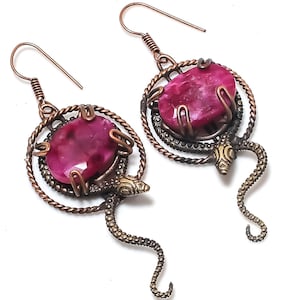 May include: A pair of earrings featuring a pink gemstone set in a copper wire design with a snake motif.