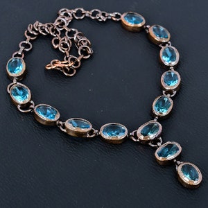 May include: A copper chain necklace with oval shaped blue gemstones. The necklace has a pendant with three blue gemstones.
