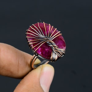 May include: A ring with a pink and white agate stone wrapped in copper wire.