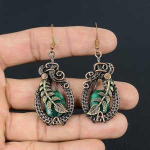 May include: A pair of copper wire earrings with green gemstone accents and a leaf design.