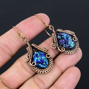 May include: A pair of copper wire wrapped earrings with blue dichroic glass teardrop shaped pendants.