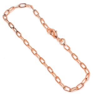 May include: A rose gold chain bracelet with oval links and a lobster clasp. The bracelet is made of a shiny, metallic material and is displayed against a white background. The chain is delicate and appears to be lightweight.