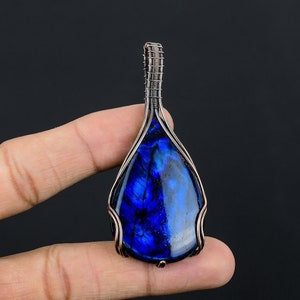 May include: A teardrop-shaped blue labradorite gemstone pendant wrapped in copper wire.