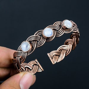 May include: A copper bracelet with a braided design and three moonstone gemstones.