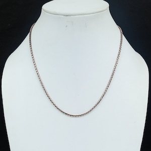 May include: A silver chain necklace on a white mannequin bust. The chain is a box style chain.