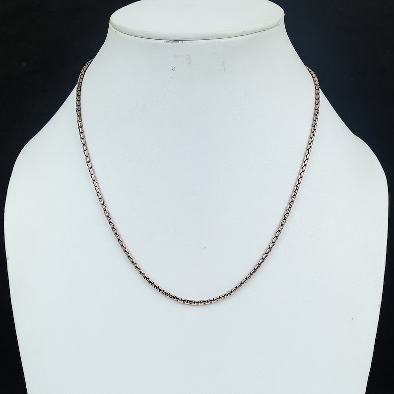 May include: A silver chain necklace on a white mannequin bust. The chain is a box style chain.