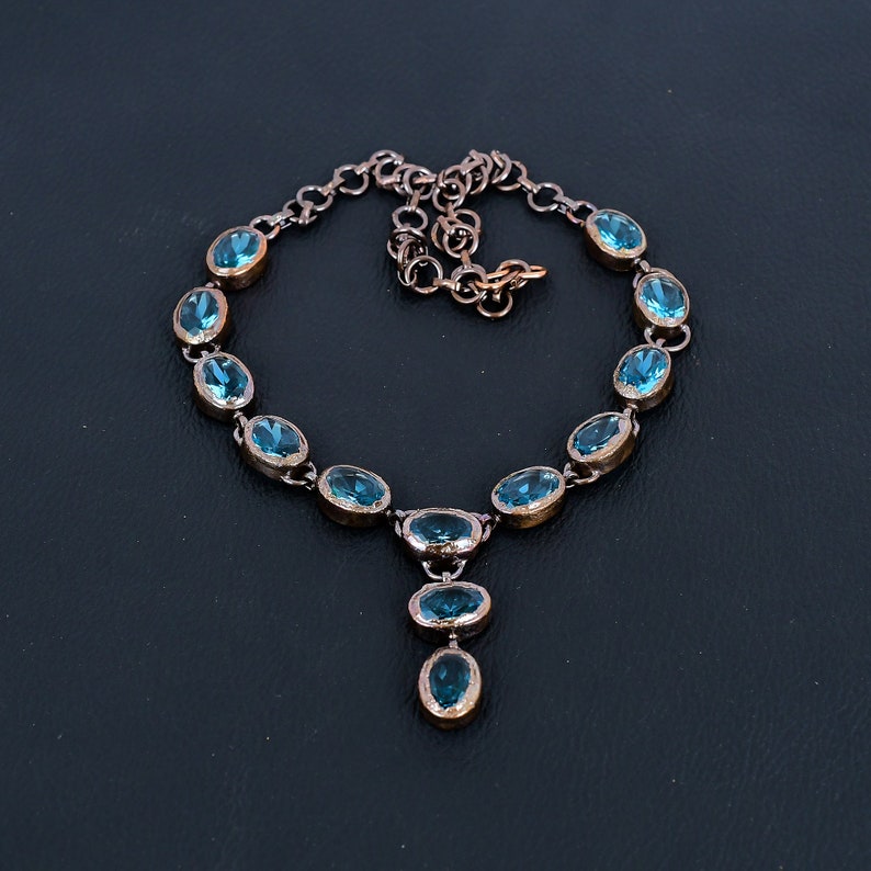 May include: A copper necklace with a pendant featuring a cluster of oval-shaped blue gemstones. The necklace has a chain with a lobster clasp.