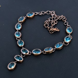 May include: A delicate blue gemstone necklace with a Y-shaped pendant. The necklace is made of silver and features oval-shaped gemstones.