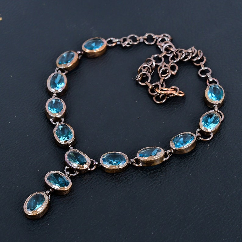May include: A delicate blue gemstone necklace with a Y-shaped pendant. The necklace is made of silver and features oval-shaped gemstones.