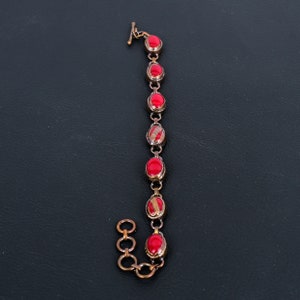 K&ouml;nnte beinhalten: Ein Kupferarmband mit einem Kettenglieddesign und roten ovalen Steinen.