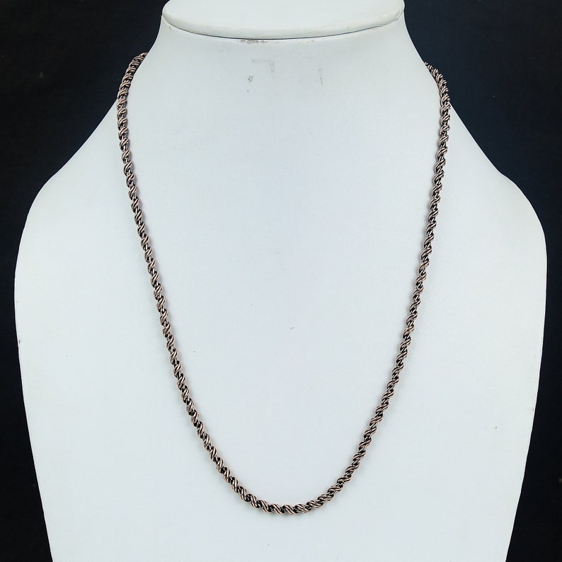May include: A silver-toned rope chain necklace on a white mannequin.