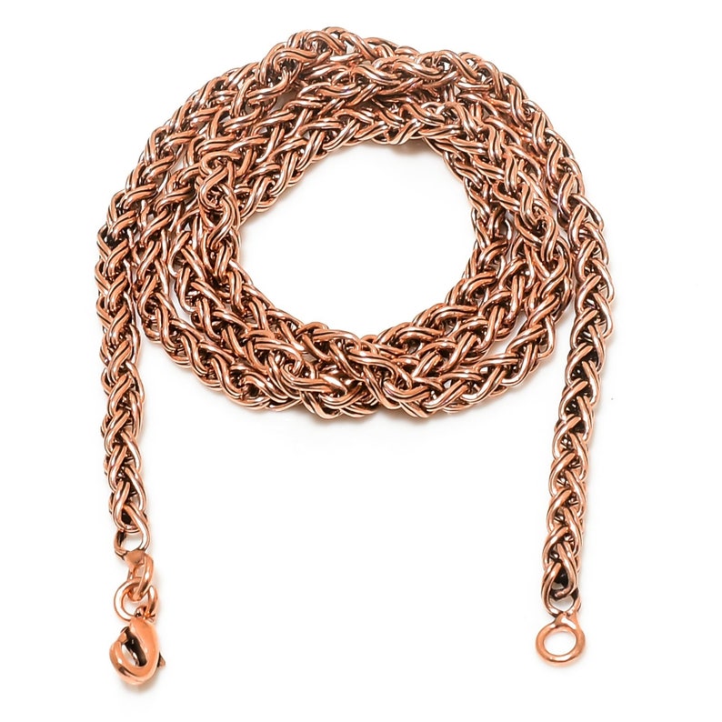 May include: A rose gold chain necklace with a braided design. The chain is coiled and the ends are visible with clasps.