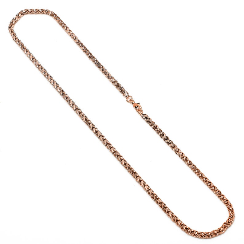 May include: A rose gold chain necklace with a braided design.