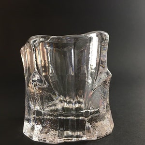 Peut inclure: Un bougeoir en verre transparent avec un design texturé et géométrique. Le bougeoir a une base large et une ouverture étroite.