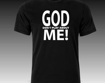May include: Black crew neck t-shirt with the white text "GOD DON'T PLAY ABOUT ME!" printed on the front. The text is in a bold, sans-serif font. The t-shirt is a basic, short-sleeved style.