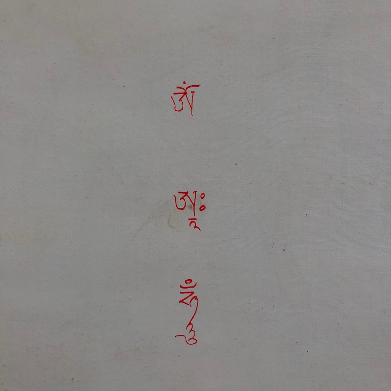 May include: Three lines of red Tibetan script on a white background. The script reads "Om Ah Hum".