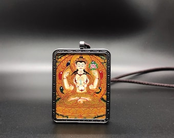 May include: A silver pendant featuring a colourful image of a deity seated in a lotus position. The image is framed in a silver border with intricate details. The pendant is on a black cord.