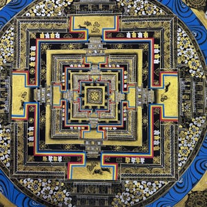 May include: A mandala with a complex geometric design in gold, blue, red, and white on a black background. The mandala is surrounded by a blue border with white and gold accents.