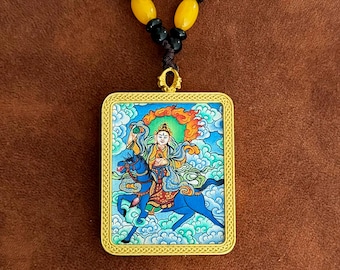 May include: A gold-framed pendant necklace featuring a colourful image of a deity riding a blue horse against a cloud background. The pendant is surrounded by an ornate border.