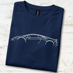 May include: A navy blue crew neck t-shirt featuring a white minimalist line art graphic of a sports car in profile. The design outlines the sleek silhouette of the vehicle, including the wheels, windows, and body panels, centred on the chest.