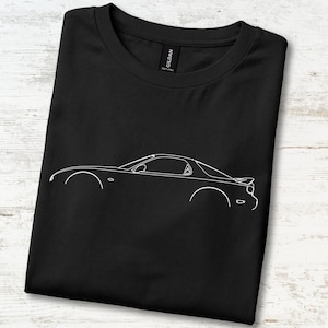 May include: A black short-sleeved t-shirt featuring a white line art illustration of a sports car in profile. The design depicts the sleek silhouette of the vehicle, including the wheels, windows, and rear spoiler. The shirt has a crew neckline.