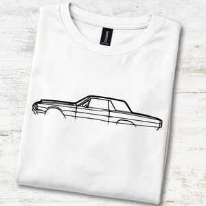 May include: A white short-sleeve t-shirt featuring a black line art illustration of a classic car in profile. The graphic depicts the side silhouette of the vehicle, including the roofline, windows, and body panels. A black Gildan brand tag is visible.