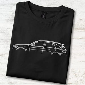 Pode incluir: Uma t-shirt preta de manga curta com um gráfico de linhas brancas de um veículo utilitário esportivo de perfil. A t-shirt tem um decote redondo e uma etiqueta da marca Gildan visível na gola interior, exibindo um design automotivo simples.