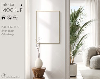 May include: A white wall with a gold frame mockup, a vase with dried branches, and a wooden stool. A large potted palm tree is visible through an open doorway.