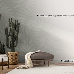 May include: A mockup of a living room interior with a gray wall featuring a white leaf pattern, a brown ottoman with a white throw blanket, and three potted cactus plants. The text "Wall - color change or use your wallpaper" and "Baseboard - color change" is visible in the image.