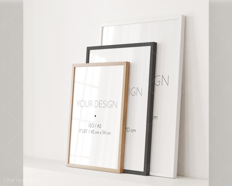May include: Three picture frames of different sizes and colors, with the smallest frame in the front and the largest frame in the back. The smallest frame is made of natural wood and has the text "YOUR DESIGN" and "ISO/A2 17x25/ 42 cm x 59 cm" printed on it. The middle frame is black and the largest frame is white.