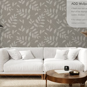 May include: A white sofa with two pillows sits in front of a wall with a light brown leafy pattern. A wooden coffee table with a book and a black cup sits in front of the sofa. The text "ADD Wallpaper" is in the top right corner of the image. The text below says "Insert your own wallpaper that will be displayed with realistic shadows. The wallpaper used in the mockup is not included."