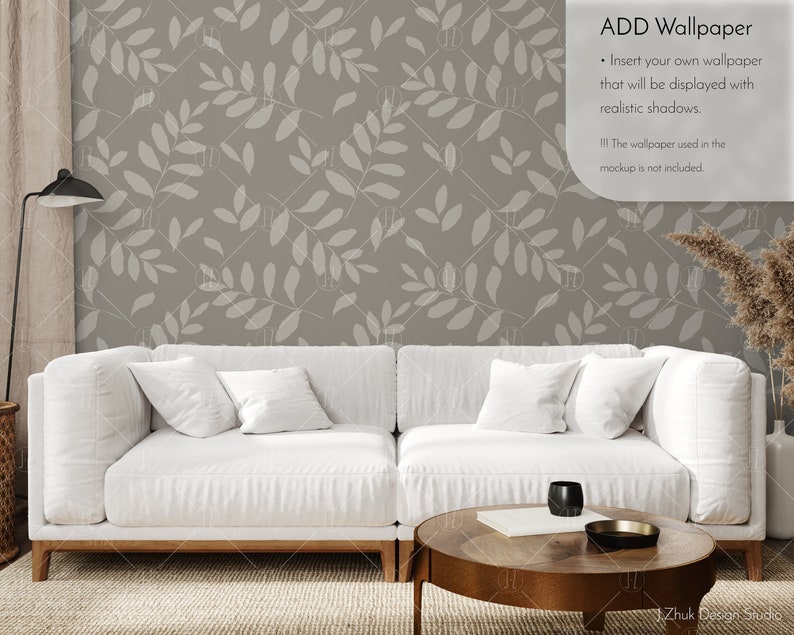 May include: A white sofa with two pillows sits in front of a wall with a light brown leafy pattern. A wooden coffee table with a book and a black cup sits in front of the sofa. The text "ADD Wallpaper" is in the top right corner of the image. The text below says "Insert your own wallpaper that will be displayed with realistic shadows. The wallpaper used in the mockup is not included."
