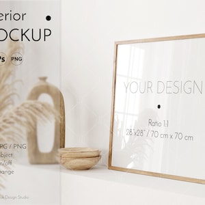 Puede incluir: Una maqueta de marco cuadrado de madera con fondo blanco y el texto "YOUR DESIGN" y "Ratio 1:1 28"x28"/70 cm x 70 cm". El marco está sentado en un estante blanco con un jarrón de madera y hierba de la pampa seca en el fondo.
